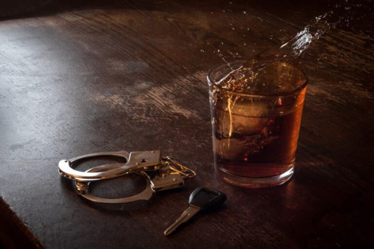 Car keys next to handcuffs and an alcoholic beverage